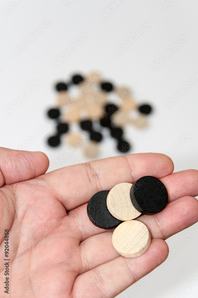 Wooden black and white chips in the hand Wooden black and white chips in the hand