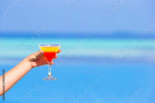 Woman holding cocktail on tropical beach