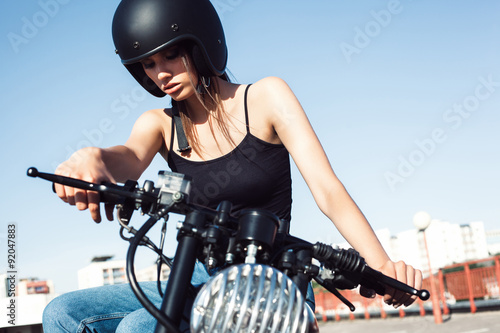 Biker girl sitting on vintage custom motorcycle photo