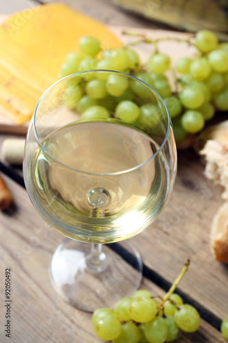 Still life of wine, grape, cheese and bread on rustic wooden background