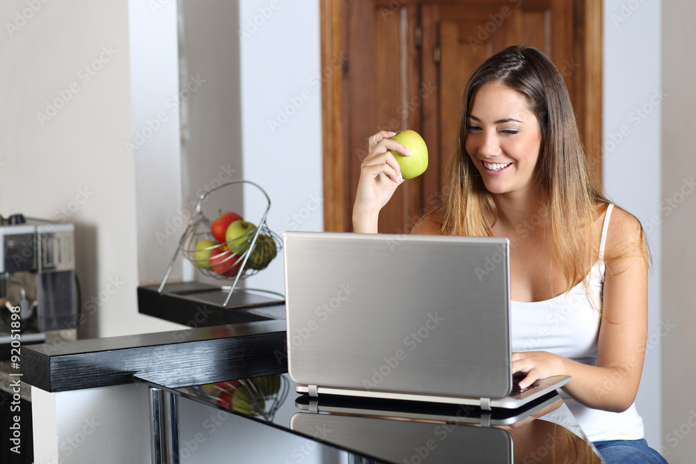 Entrepreneur woman browsing a laptop and eating at home Entrepreneur woman browsing a laptop and eating at home