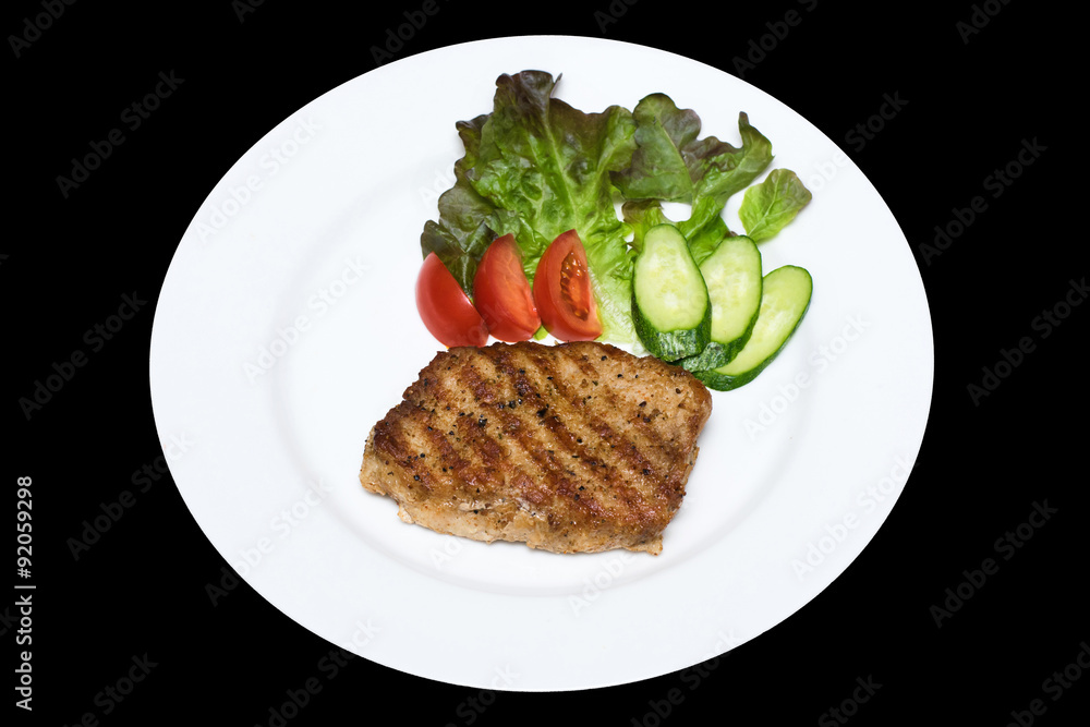 photo of a pork stake on a white plate with a cucumber, tomato a photo of a pork stake on a white plate with a cucumber, tomato a