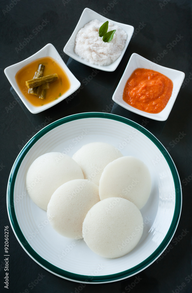 Indian idly with chutney and sambar - A traditional south Indian breakfast of fresh steamed Indian Idly (Idli / rice cake) served with tomato chutney, coconut chutney and sambar. Natural light used. Indian idly with chutney and sambar - A traditional south Indian breakfast of fresh steamed Indian Idly (Idli / rice cake) served with tomato chutney, coconut chutney and sambar. Natural light used.