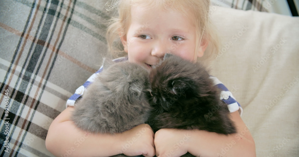Cheerful little girl holding two fluffy kittens Cheerful little girl holding two fluffy kittens