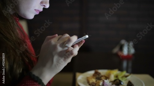 Beautiful girl looking in the smartphone in the restaurant