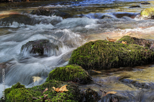 Flowing water over stones with green moss.