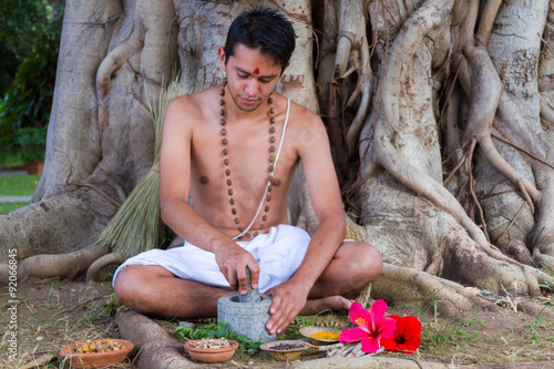 Fotografie A young man preparing ayurvedic medicine in the traditional manner in India