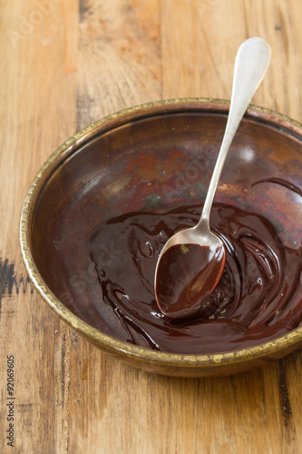 chocolate in dish with spoon on brown wooden background