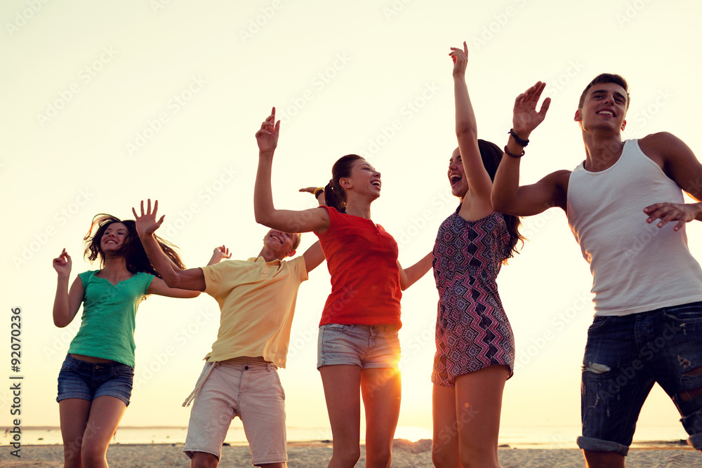 Obraz premium smiling friends dancing on summer beach