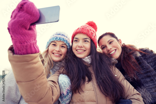 happy teenage girls taking selfie with smartphone