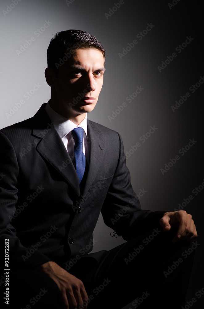 Fototapeta premium Young businessman in dark studio