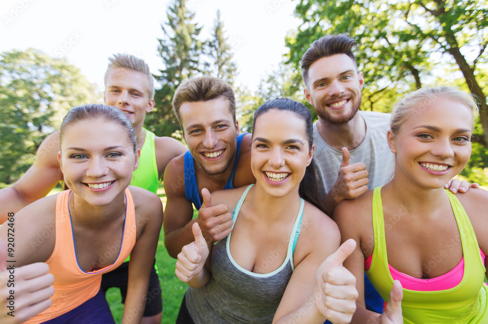 group of happy sporty friends showing thumbs up group of happy sporty friends showing thumbs up