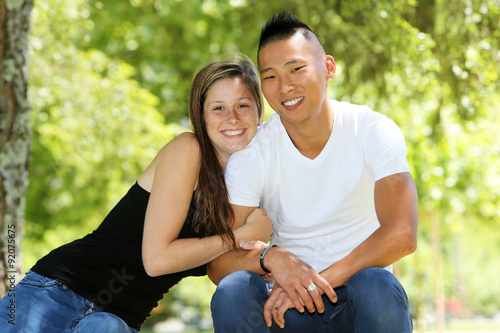 Young mixed couple sitting on a bench in a park