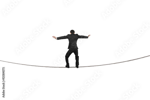 Fototapeta Rear view of businessman balancing on tightrope