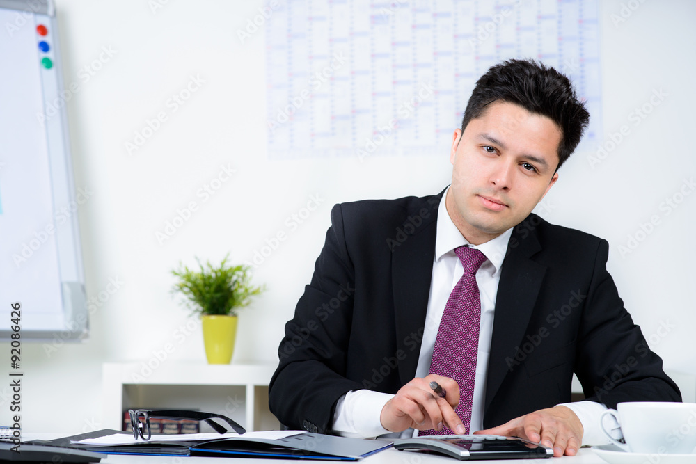 Businessman Calculating Financial Data At Desk Businessman Calculating Financial Data At Desk