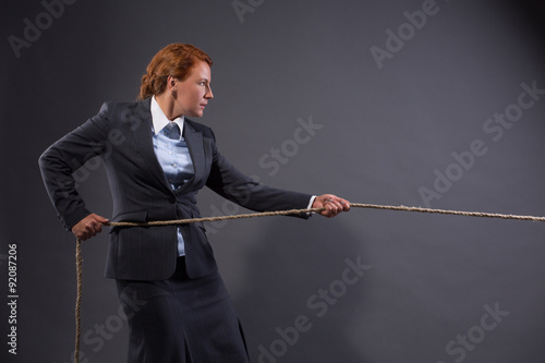 Businesswoman hauling at a rope