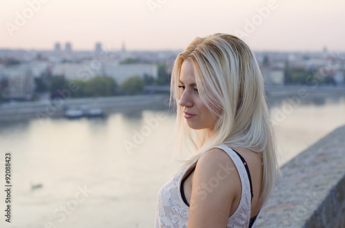 Beautiful pensive blonde girl by the river side, feeling lonely. Soft focus 