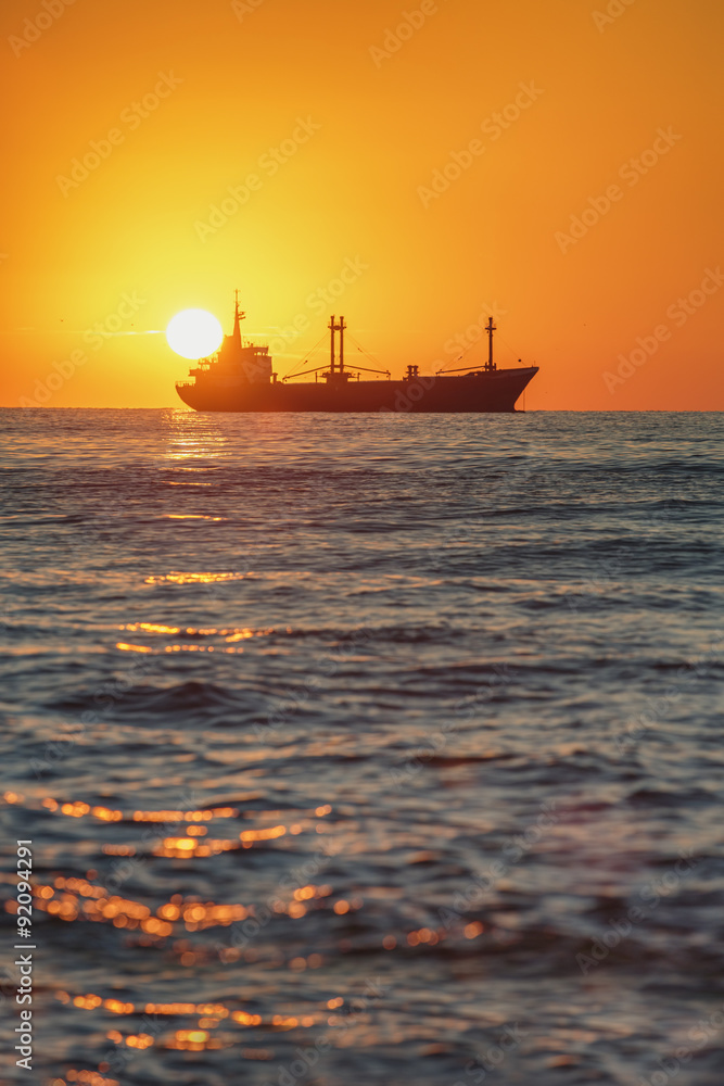 Cargo ship sailing at sunrise near the harbour