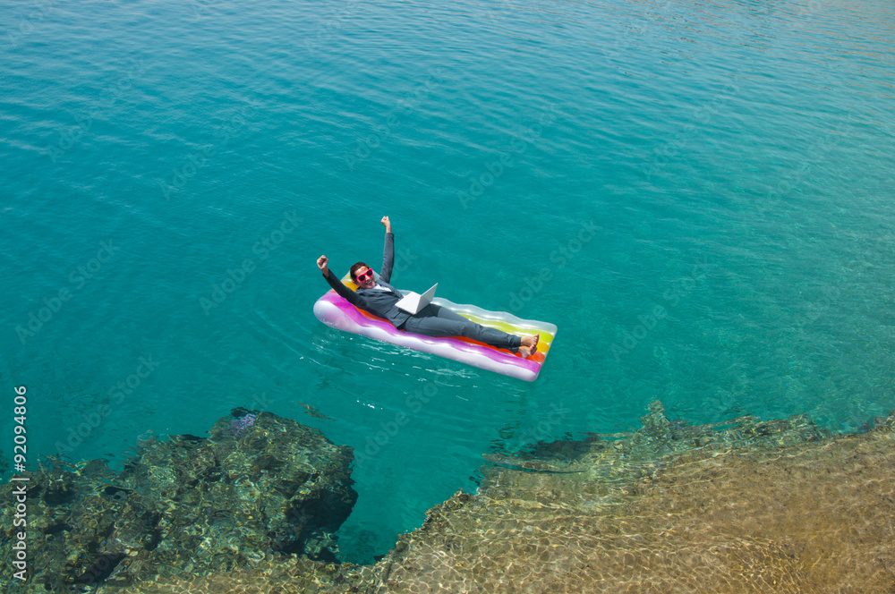 Fototapeta premium Successful businesswoman with laptop on floating mattress in red sea