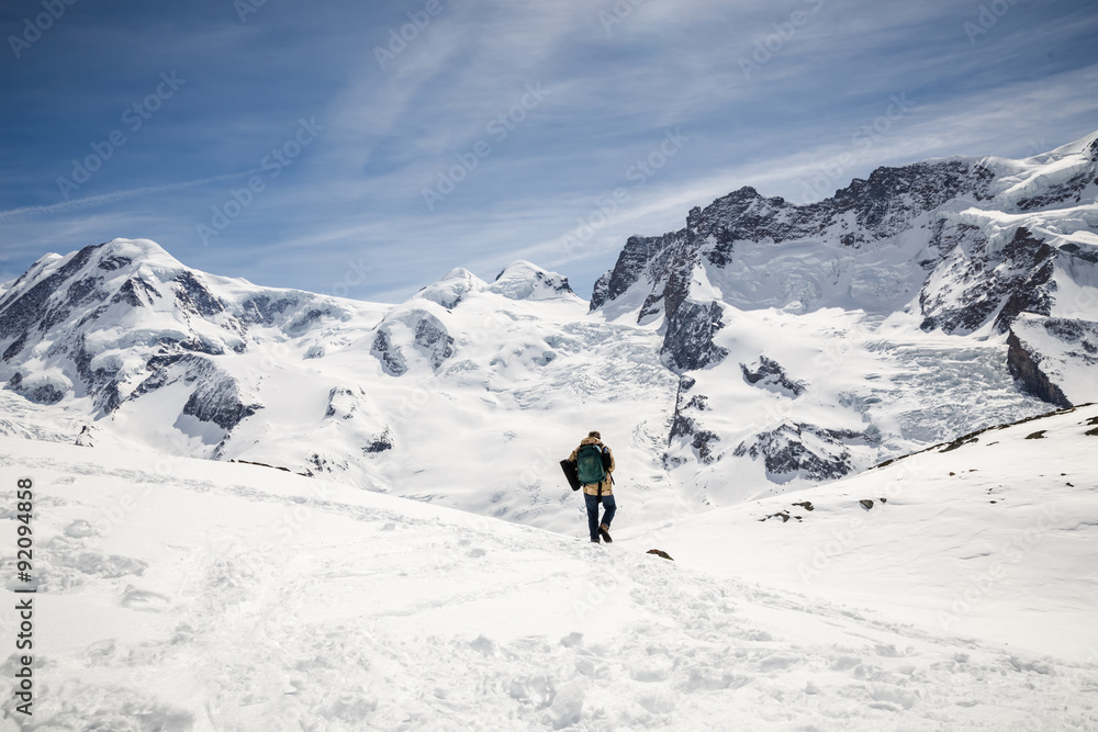 Man walking on the snow with the background of snow mountain.