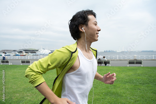 Happy young asian man running in city park