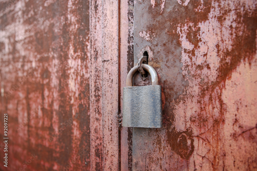 On the old wooden door, installed a rusty padlock On the old wooden door, installed a rusty padlock