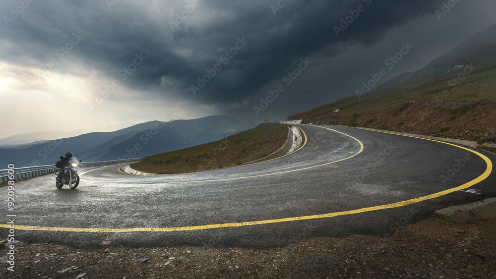 Obraz premium Jazda motocyklem na autostradzie alpejskiej w kierunku burzy