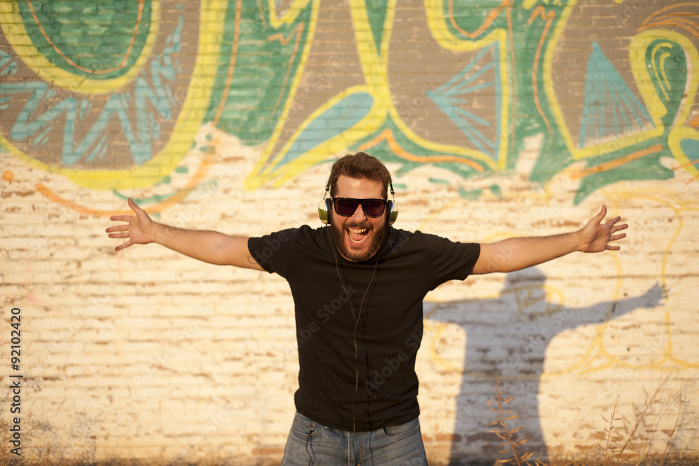 Obraz premium Chico atractivo y joven ecuchando música con auriculares, sonriendo y cantando