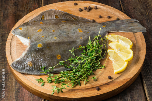 Fotografie, Tablou Fresh raw plaice with pepper, thyme and lemon on the board