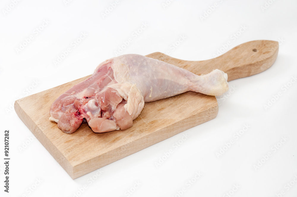Chicken drumstick on the wooden board over white background