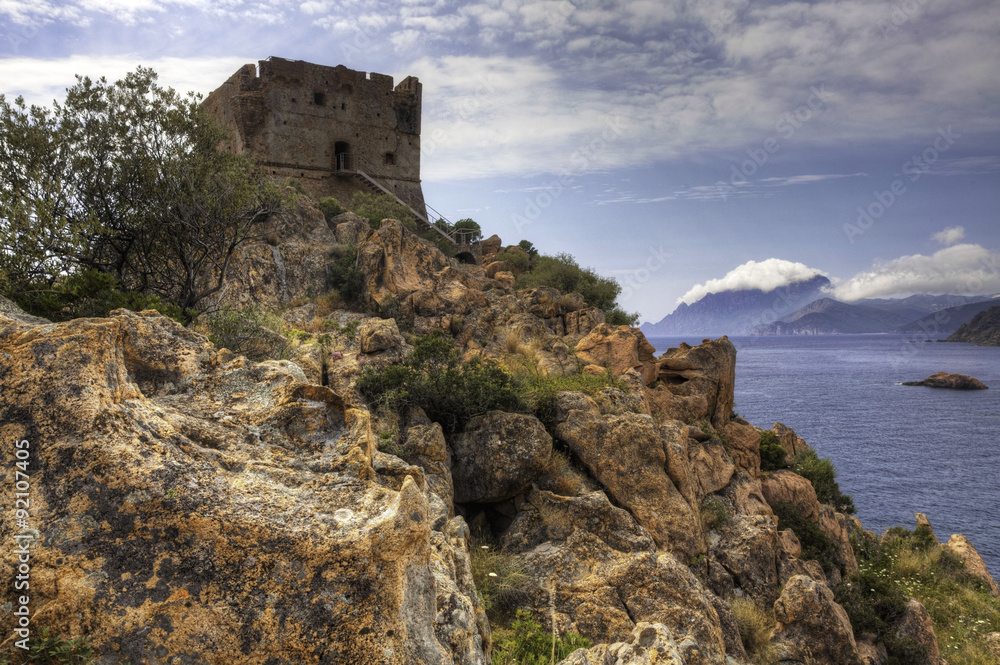 A colorful coastal view with a stone tower in Corsica, France