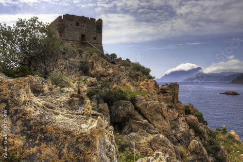 A colorful coastal view with a stone tower in Corsica, France