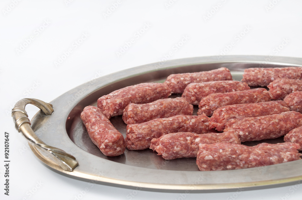 Raw kebabs aligned on the metal tray Raw kebabs aligned on the metal tray
