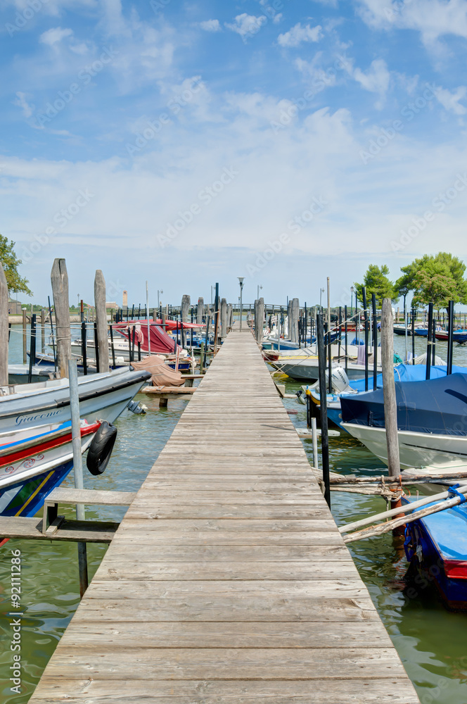 Wooden pier with boats in the main harbour of Burano island Wooden pier with boats in the main harbour of Burano island