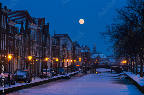 Oude Rijn in Leiden, the Netherlands. A full moon rises over the city canal seen from a bridge