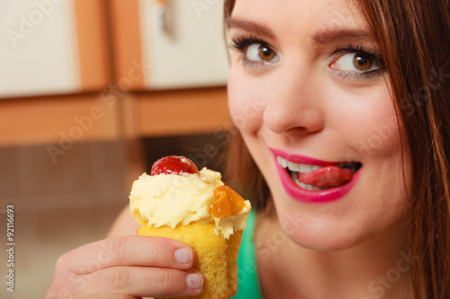 Woman eating cake licking her lips. Gluttony.