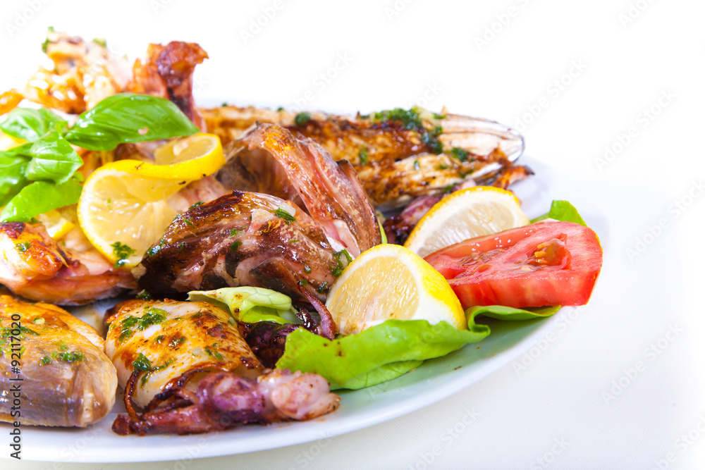 Grilled fish with vegetables on plate. Isolated on a white Grilled fish with vegetables on plate. Isolated on a white