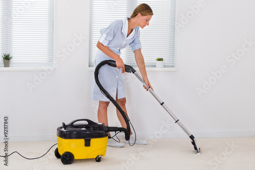 Female Maid Cleaning With Vacuum Cleaner