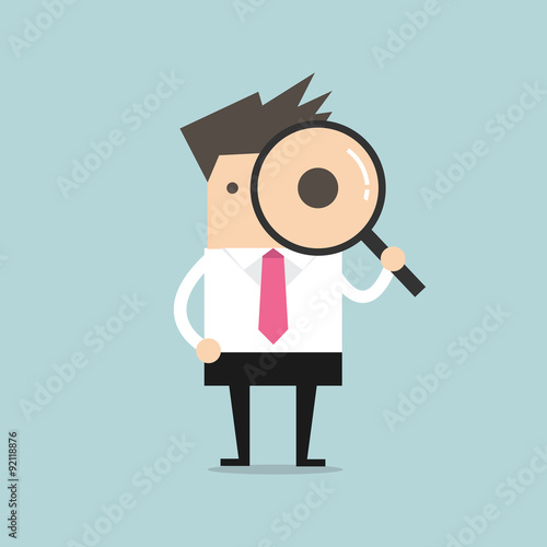 Businessman looking through a magnifying glass