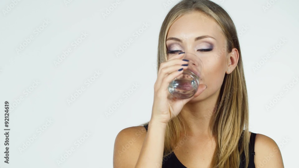 Attractive blonde woman drinks water on a white background Attractive blonde woman drinks water on a white background