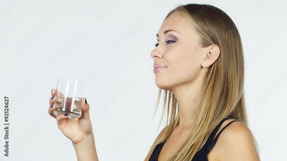 Attractive blonde woman drinks water on a white background Attractive blonde woman drinks water on a white background