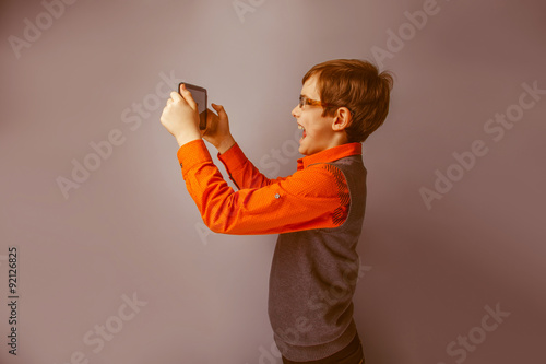 European-looking boy of ten years in glasses holding tablet i