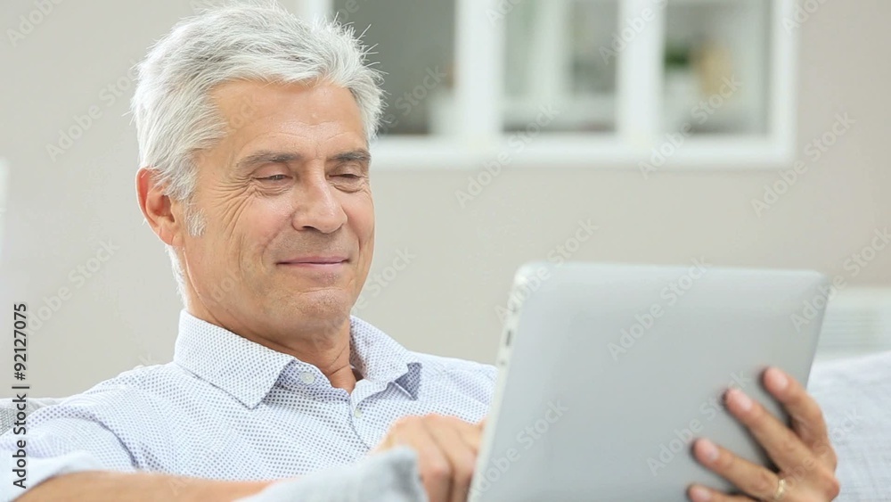 Senior man relaxing in sofa and using digital tablet Senior man relaxing in sofa and using digital tablet