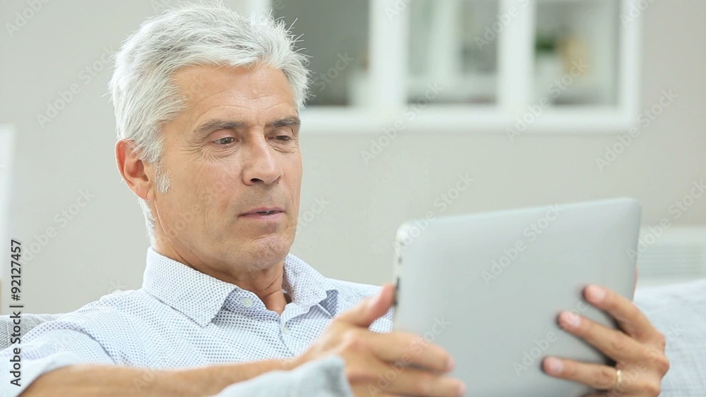 Senior man relaxing in sofa and using digital tablet Senior man relaxing in sofa and using digital tablet