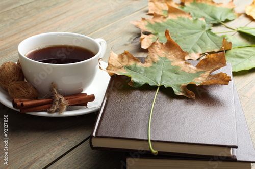 Cup of tea with cinnamon and a book and walnut on wooden background