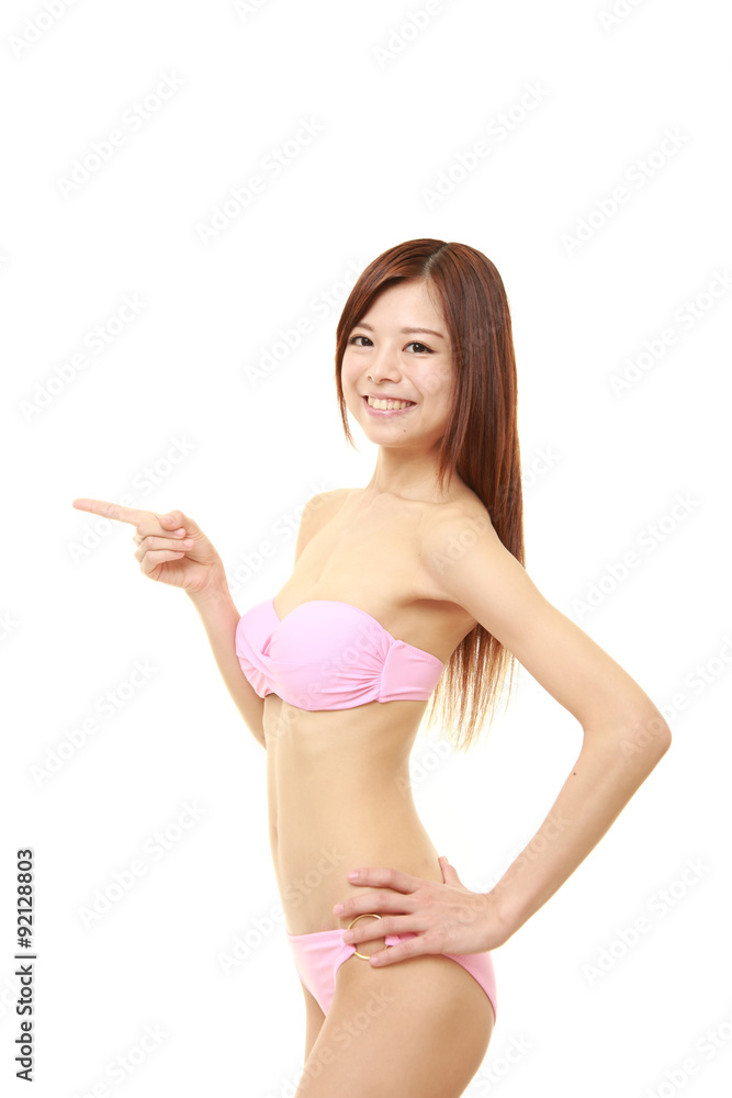young Japanese woman in a pink bikini presenting and showing something young Japanese woman in a pink bikini presenting and showing something