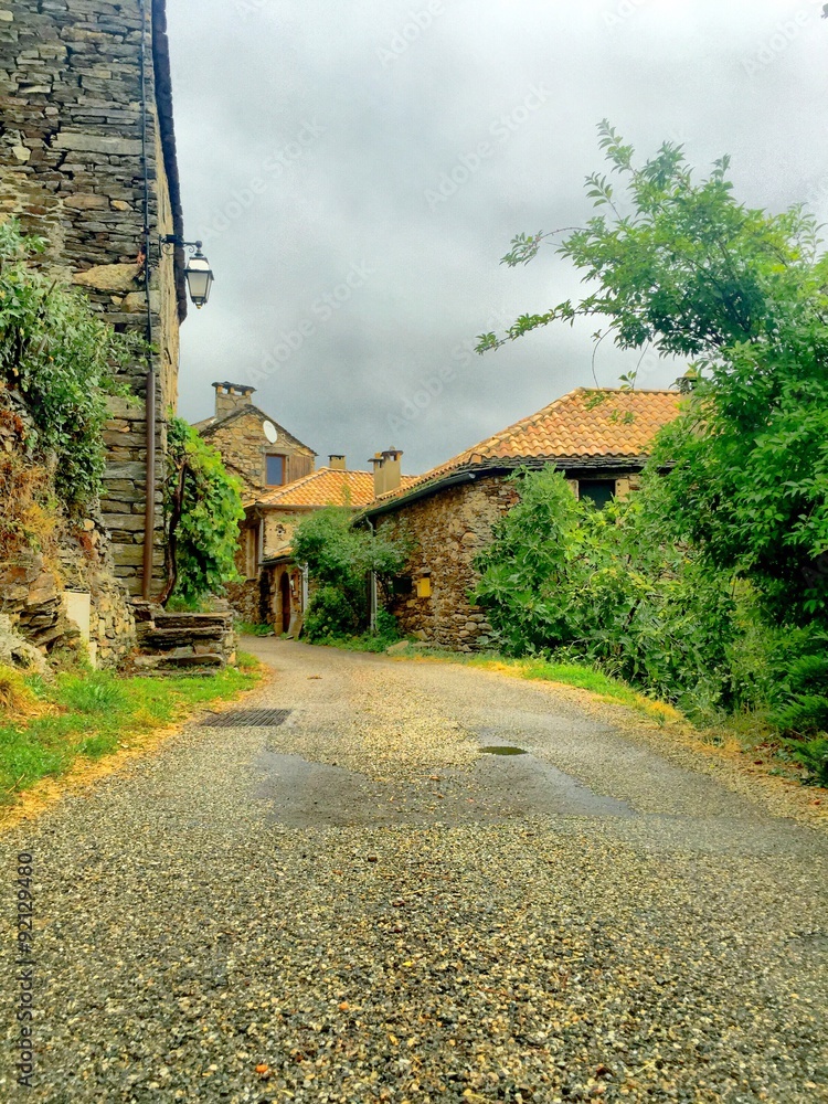 Obraz premium Quiet lane leading between stone houses with tiled roofs in an Ardèche mountain village, France, vertical