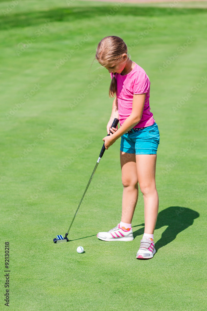 Fototapeta premium Cute little girl playing golf on a field
