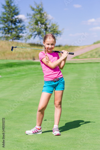 Cute little girl playing golf on a field
