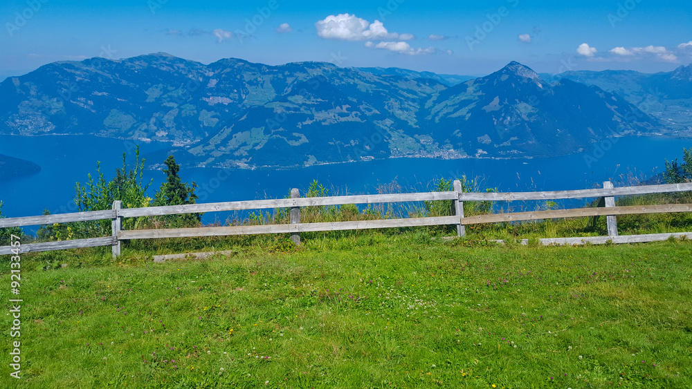 Fototapeta premium Green field surrounded by fence across the mountain